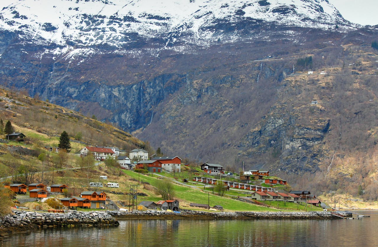 Picturesque village nestled in a Norwegian fjord, surrounded by snowy mountains and tranquil waters.