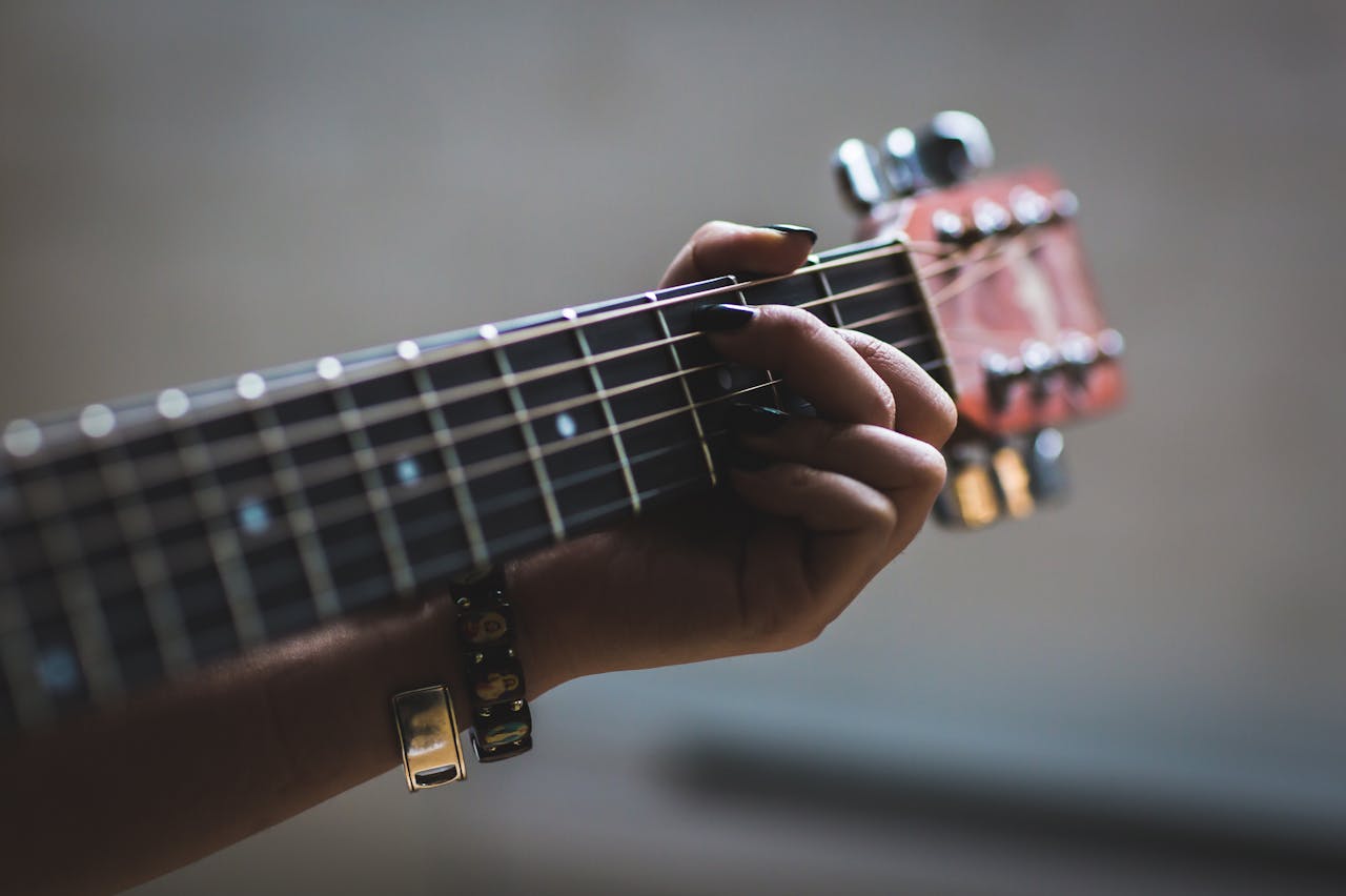 about-img A musician's hand skillfully playing an acoustic guitar, focusing on the fretboard and strings.