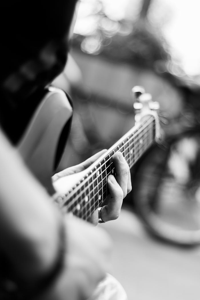 about-02 Close-up of a guitarist's hands on the fretboard in black and white.